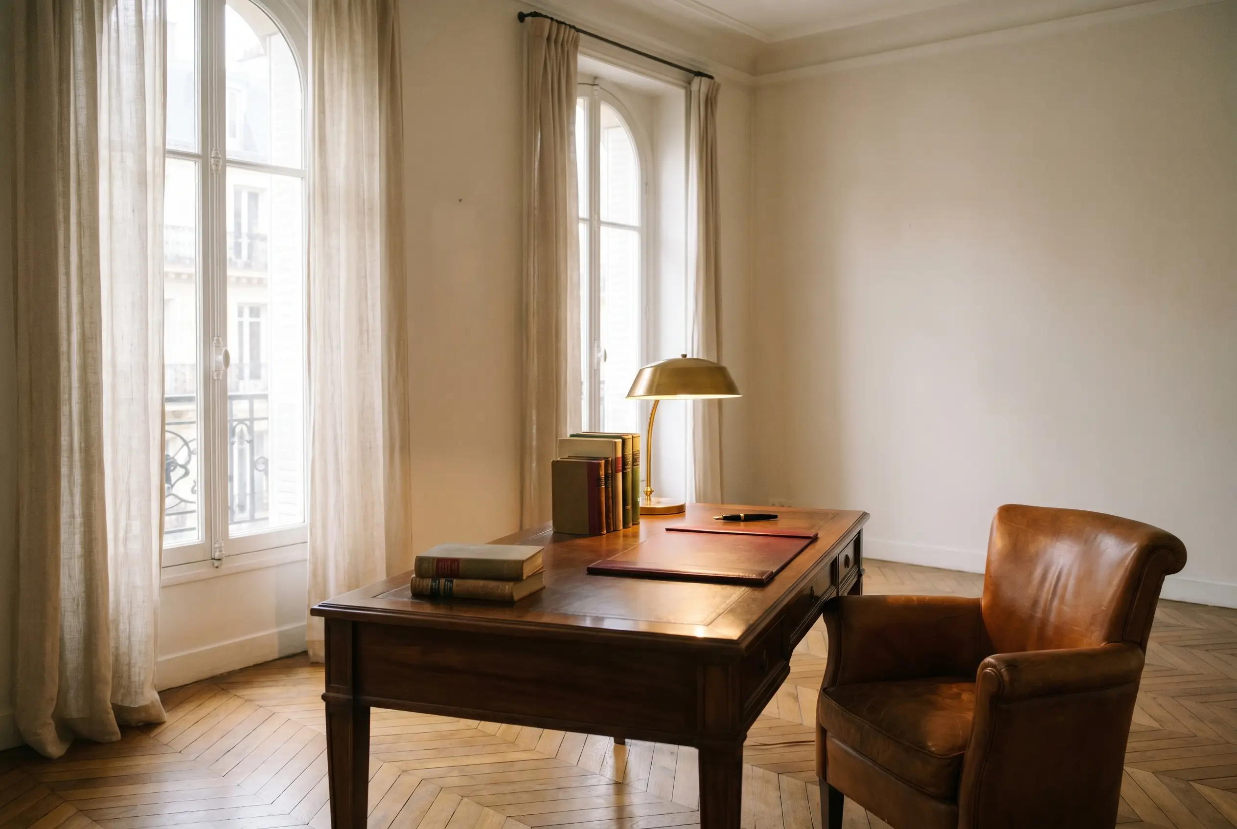 Bureau feutré d'un cabinet de gestion de patrimoine : parquet en chevrons, bois et lampe en laiton